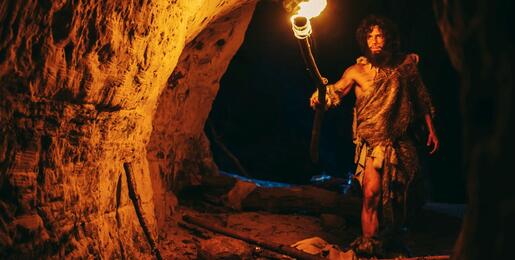 Prehistoric man exploring a cave by torchlight