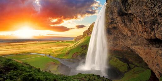 Seljalandsfoss, Iceland - flowing white waterfall in foreground, setting sun in background