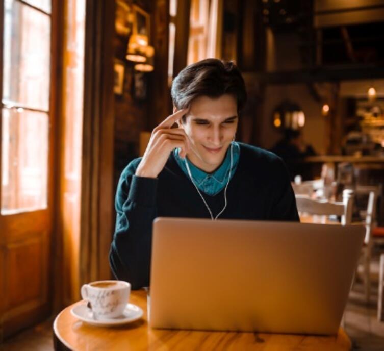 Person sitting in a coffee shop looking at a laptop computer